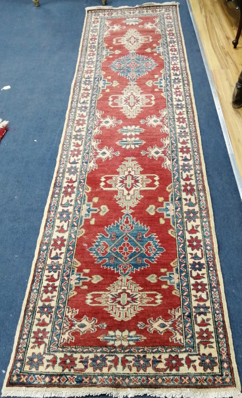 A Caucasian style red ground runner, 307 x 80cm